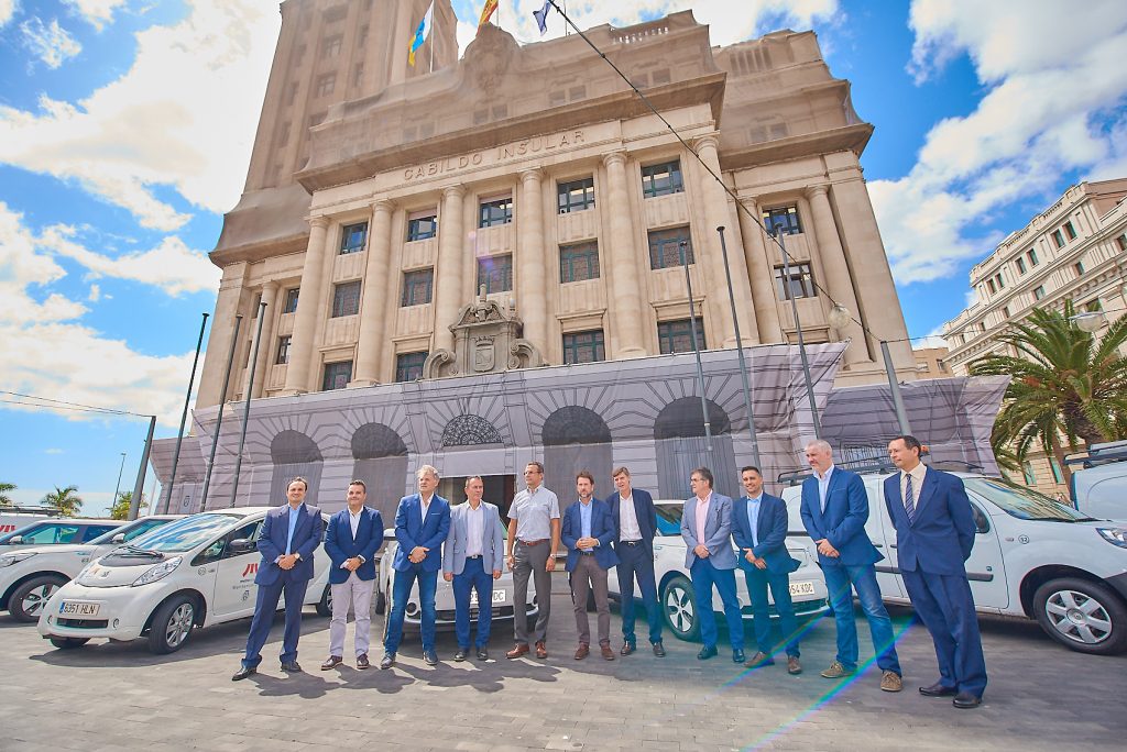 Autoridades de la Corporación Insular, de Metrotenerife y de entidades colaboradoras posan delante de los vehículos eléctricos en el exterior del Cabildo